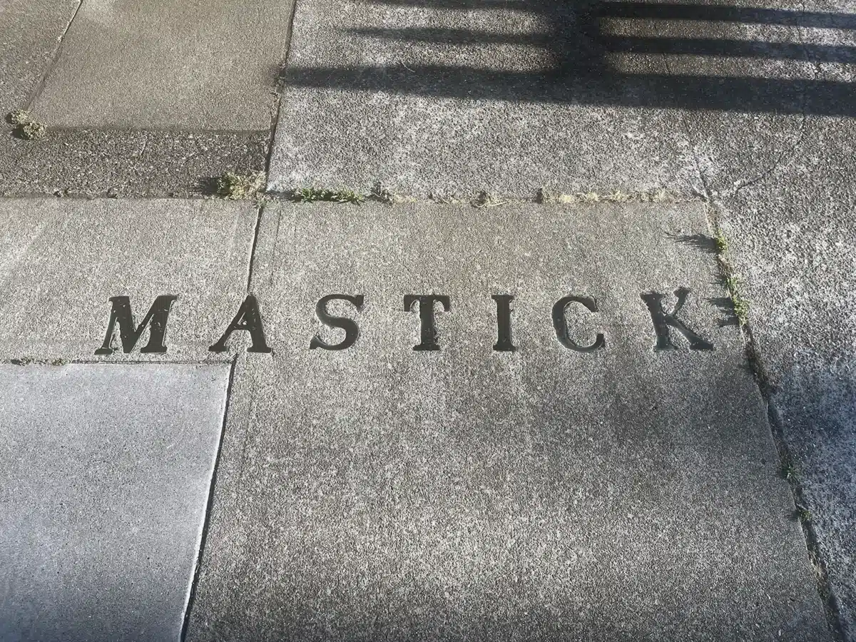 Alameda Post - The name "Mastick" spelled out in metal letters embedded in a sidewalk 