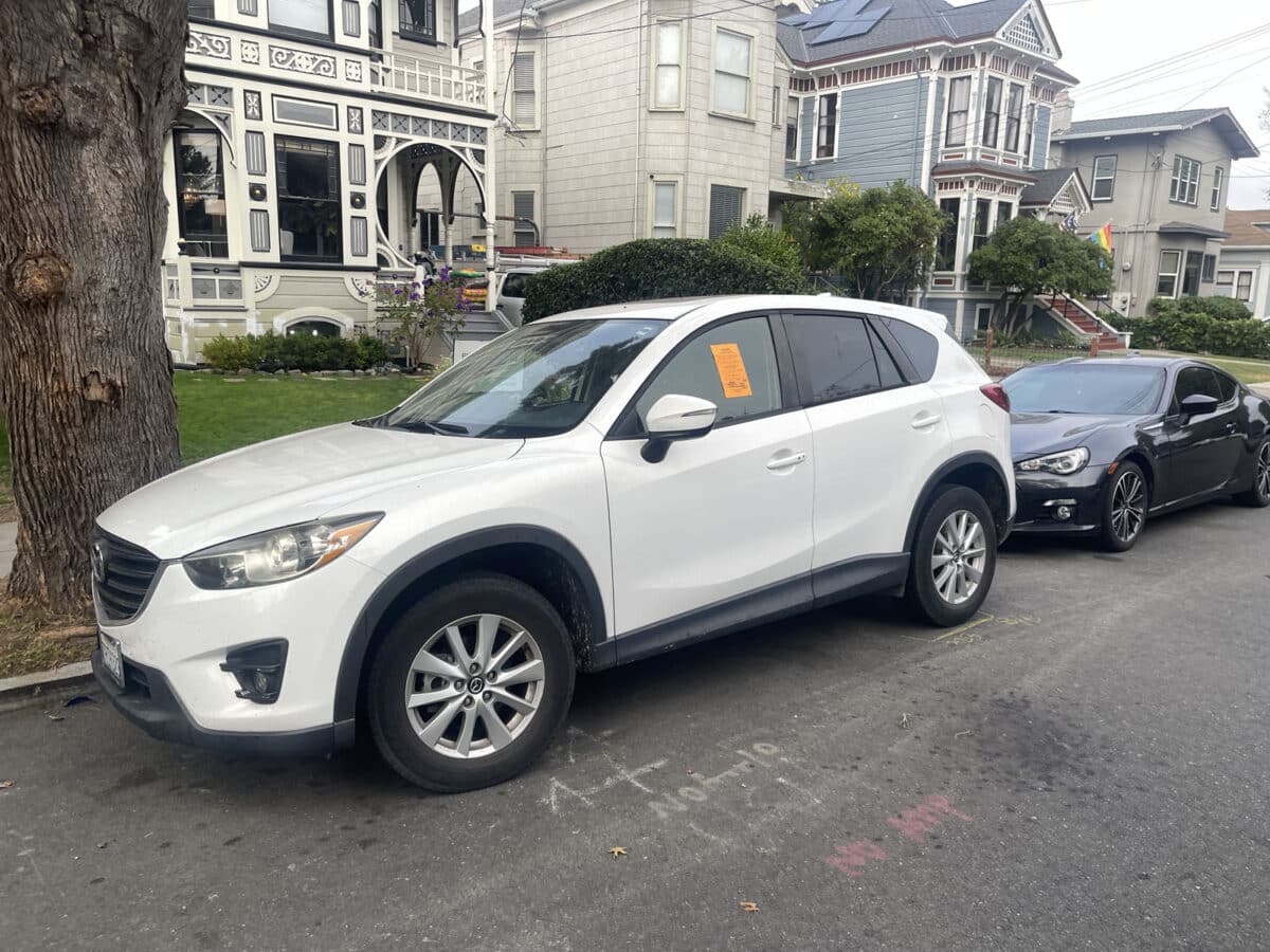 Alameda Post - a photo of a white car with a orange sticker on the outside of the driver's side window