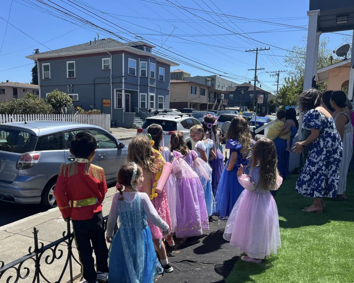 Alameda Post - a group of excited children in princess costumes look at a patrol car procession