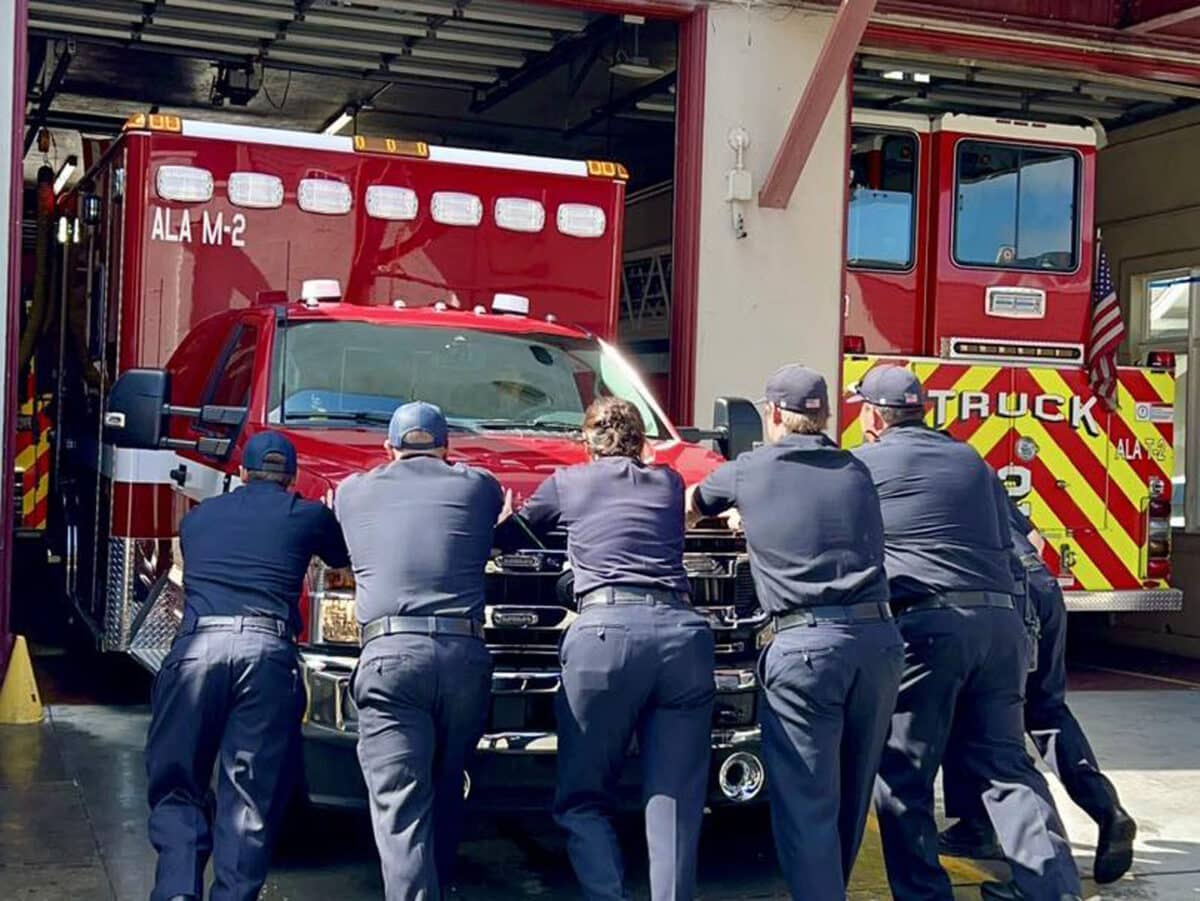 Alameda Post - firefighters push a new ambulance into its bay