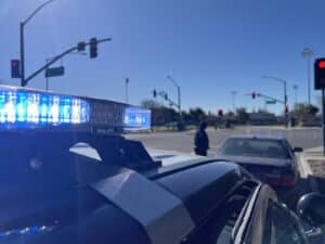 Alameda Post - a photo of a police car and officer standing at a stopped car. The image accompanied a story of APD arresting a potential bank robber