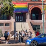 Alameda Post - City Hall with a pride flag and a group of people gathered in front
