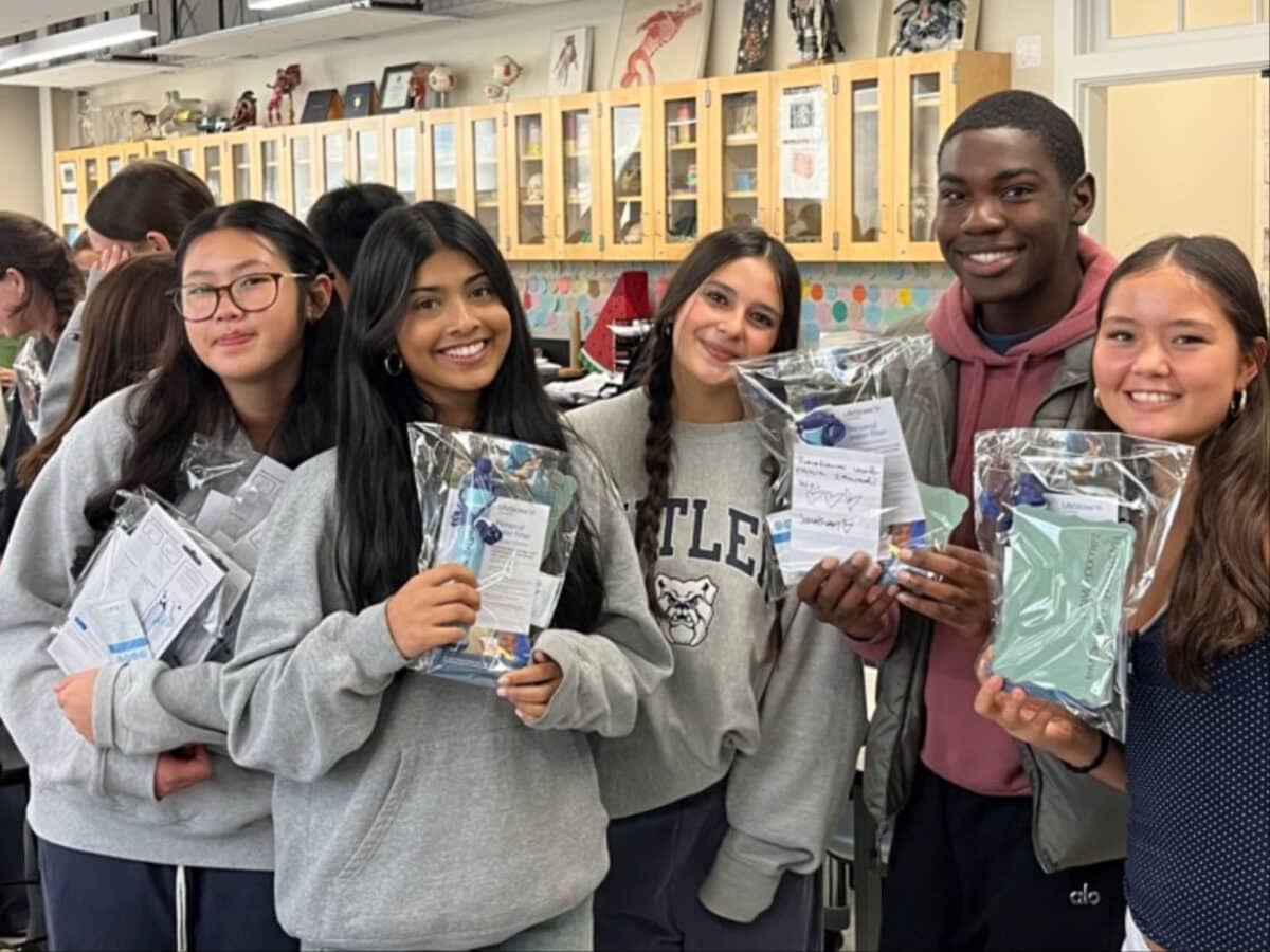 Alameda Post - Five AHS students in the AguaEmpowers club smile and hold kits they have assembled. 