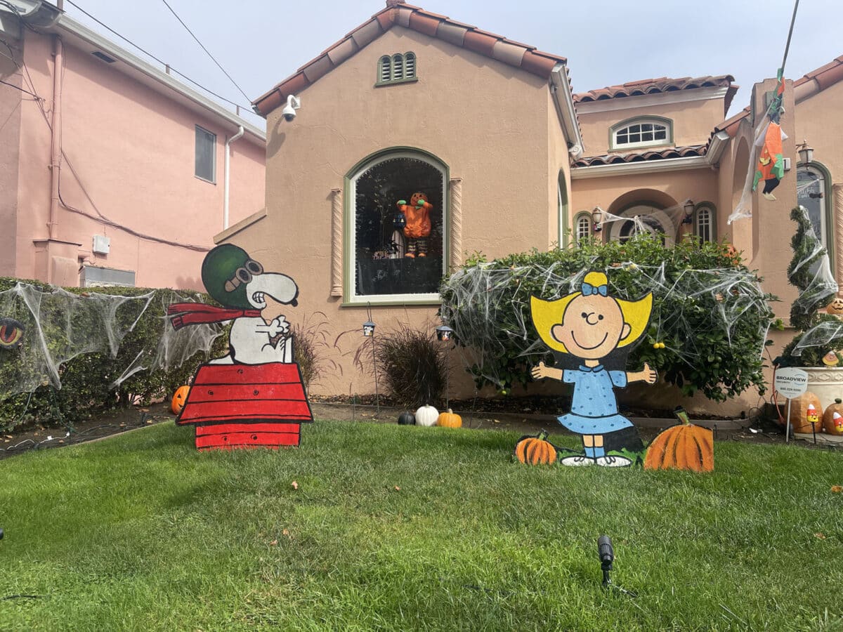Alameda Post - On a front lawn, large and well drawn cutouts of Snoopy and Sally from Charlie Brown sit by pumpkin decor. 