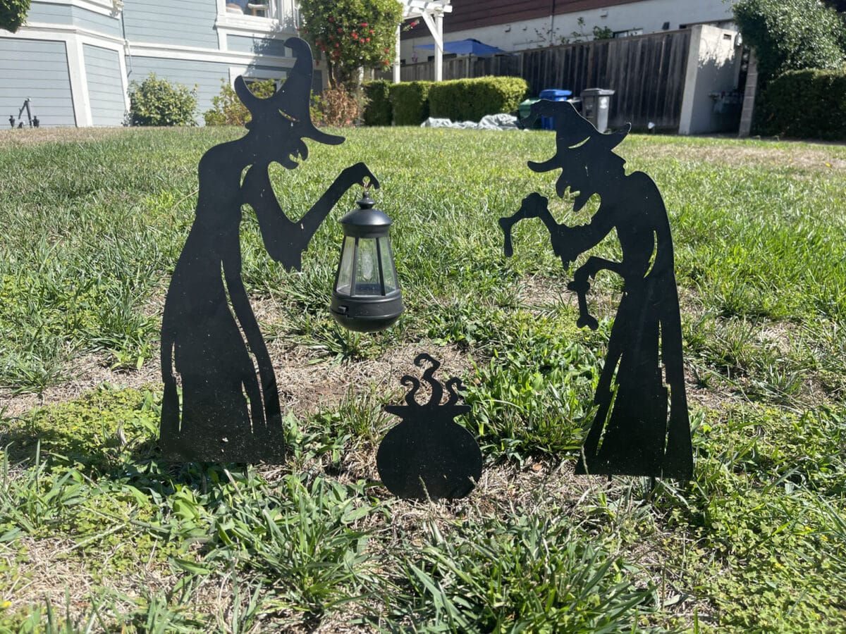Alameda Post - Halloween decor in a yard. It's metal silhouettes of witches over a cauldron.