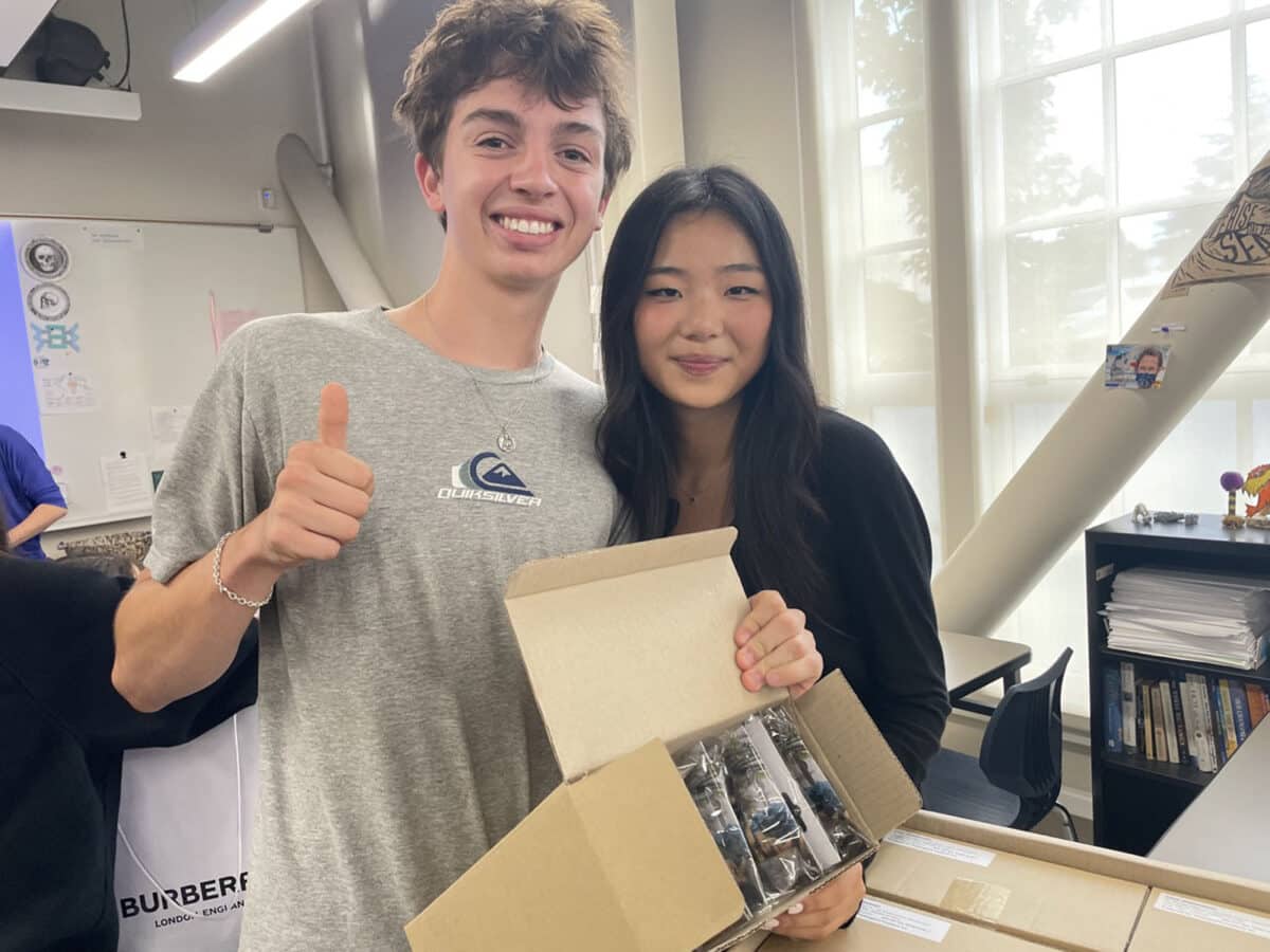 Alameda Post - Two students at AHS smile and hold supplies.