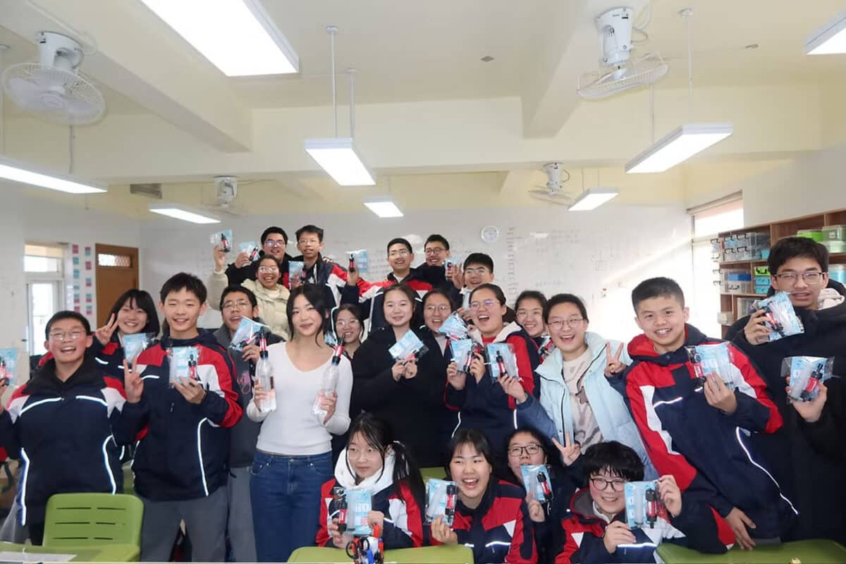 Alameda Post - An AHS student stands amongst students from a Chinese school. They all hold up water filtration kits and smile.