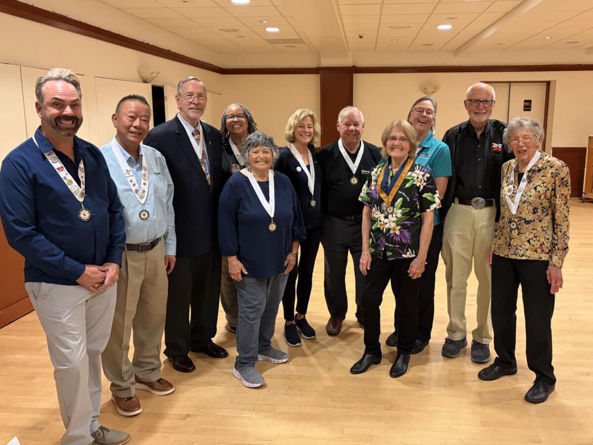 Alameda Post - A group of Alameda Kiwanis stand and smile. Most are wearing medals around their necks. 