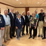 Alameda Post - A group of Alameda Kiwanis stand and smile. Most are wearing medals around their necks.