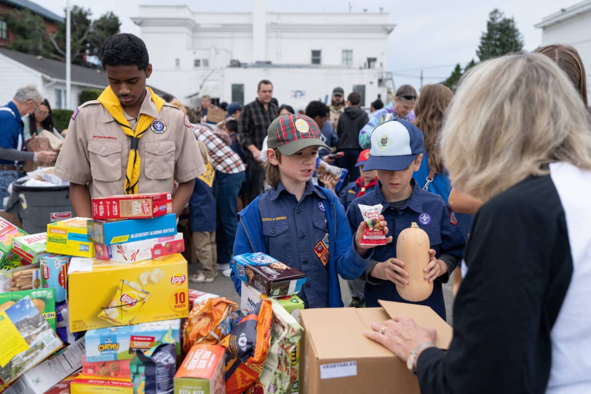 Alameda Post - Scouts stand around a large table of food and sort the items.