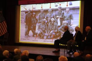 Alameda Post - Onstage at the Alameda Elks Lodge, a slideshow shows an old photo of servicemembers from the Vietnam War.