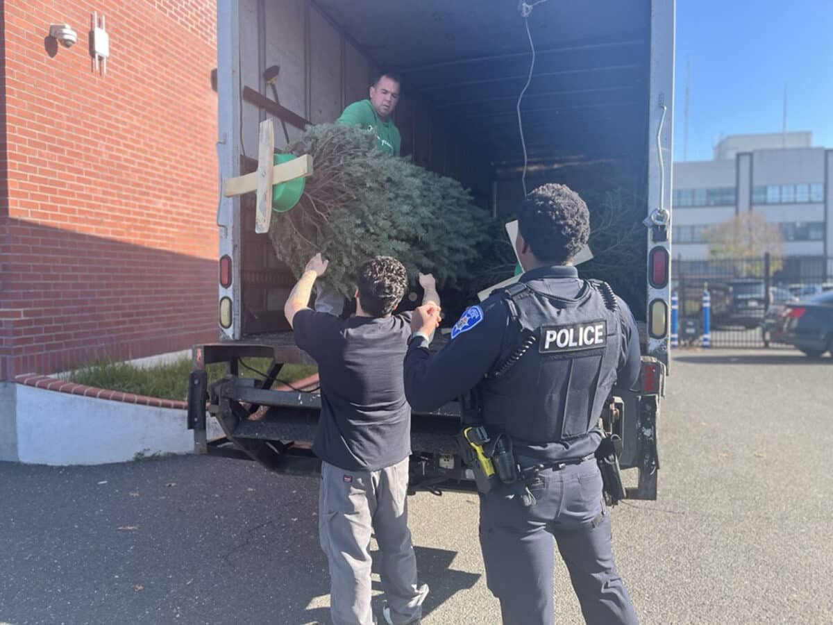 Alameda Post - APD officers unload a Christmas tree from the back of a truck. 
