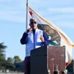 Alameda Post - Superintendent Pasquale Scuderi speaks into a microphone behind a podium outdoors at the new Enincal field.