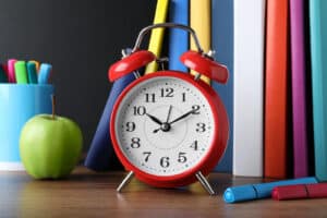 Alameda Post - an alarm clock in front of school supplies on a desk.