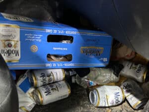 Alameda Post - A cardboard beer box and empty beer cans in the back of a vehicle.