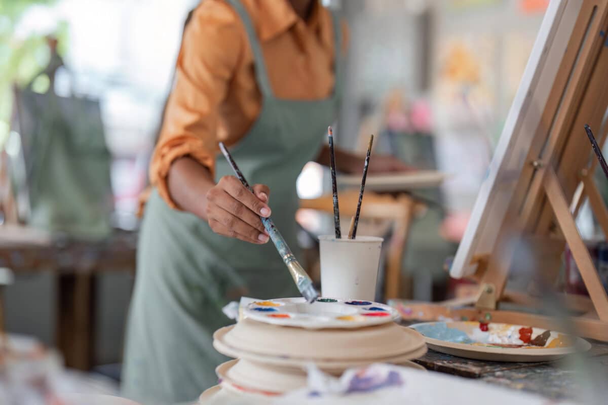 Alameda Post - A woman reaches a paintbrush towards a palette. 