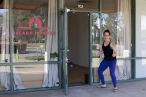Alameda Post - A woman stands outside the door to Island Inferno and holds a thumbs up.