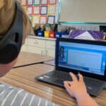 Alameda Post - An elementary schooler wears headphones and used a program on a laptop.