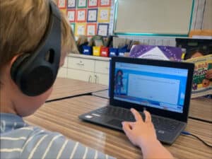 Alameda Post - An elementary schooler wears headphones and used a program on a laptop.