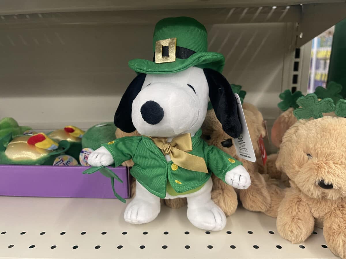 Alameda Post - A toy plush snoopie sits on a store shelf wearing a saint patrick's day outfit. 