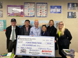 Alameda Post - Kevin McNulty smiles and holds a large check from AEF next to five other people.
