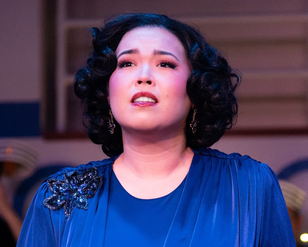 Alameda Post - A woman with short curly black hair wears a blue dress and looks into the distance.