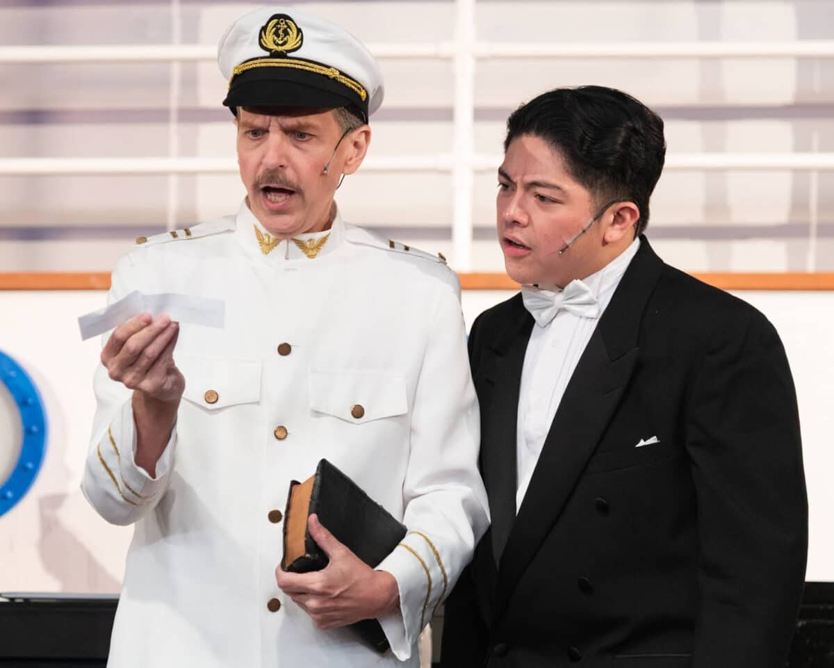 Alameda Post - An actor dressed as a ship captain and an actor in a black suit look at a small slip of paper together.