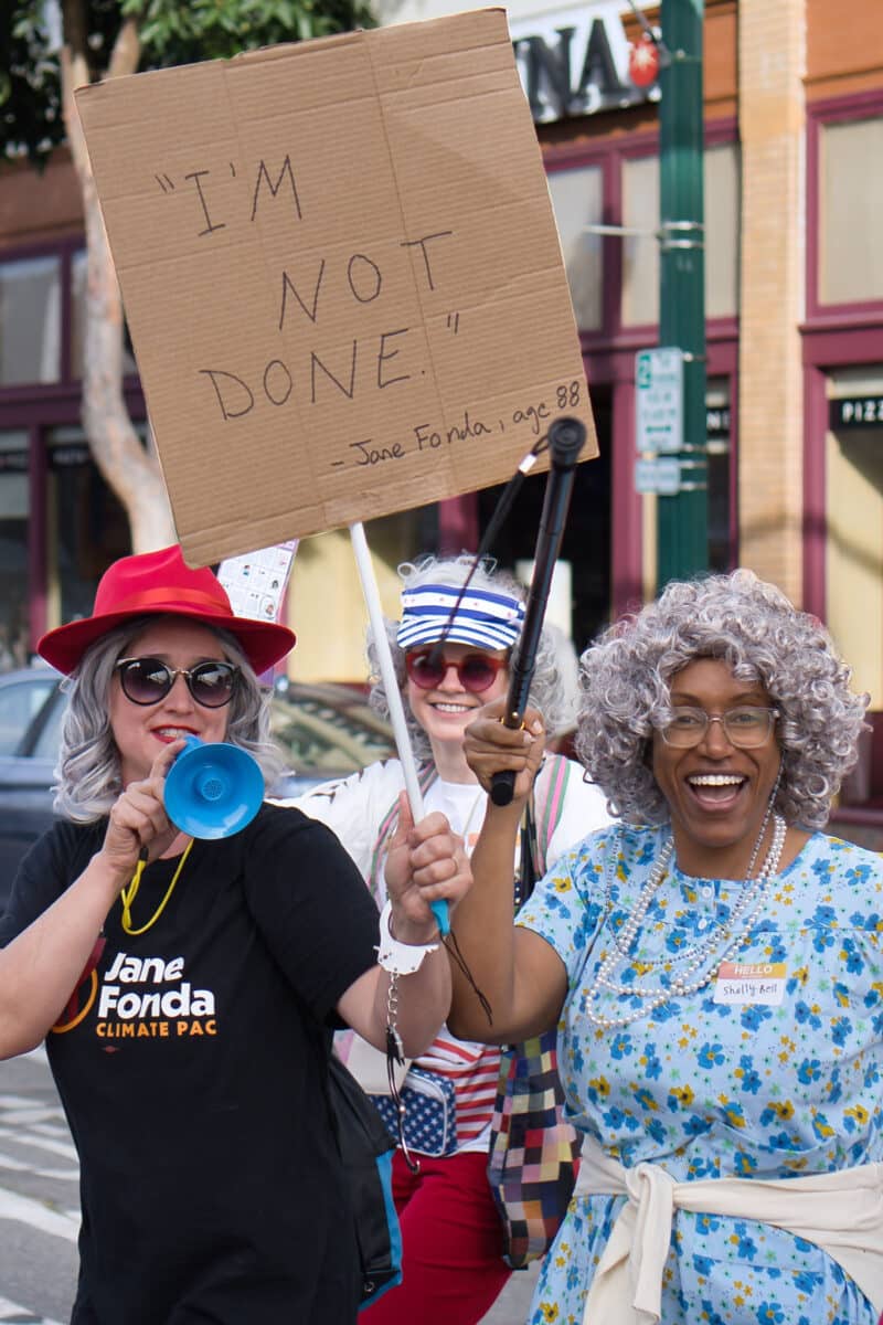 Alameda Post - Participants dressed as grannies for GrannyCon 2026. One holds a sign that says "I'm not done."