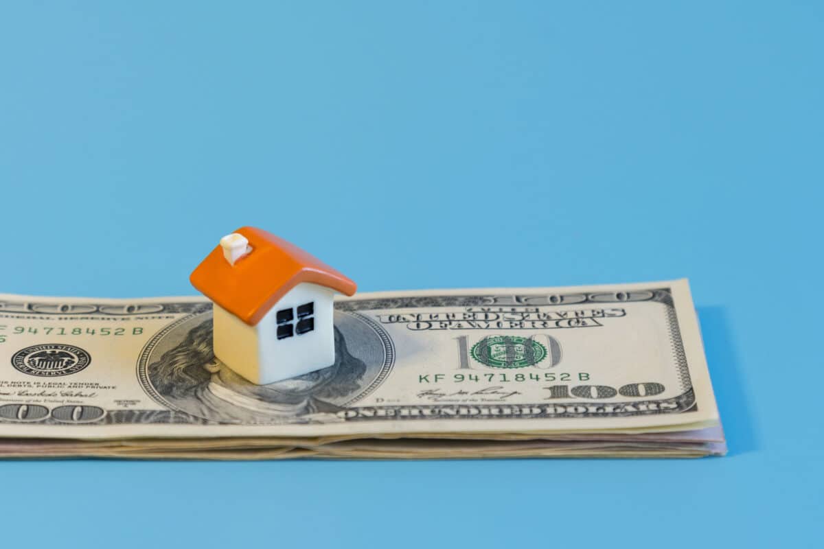 Alameda Post - A small model of a house on top of a stack of money.