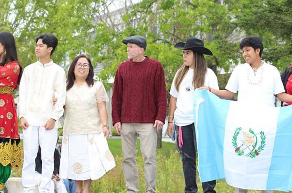 Alameda Post - A group of students and adults stand wearing different outfits. One holds a flag. 
