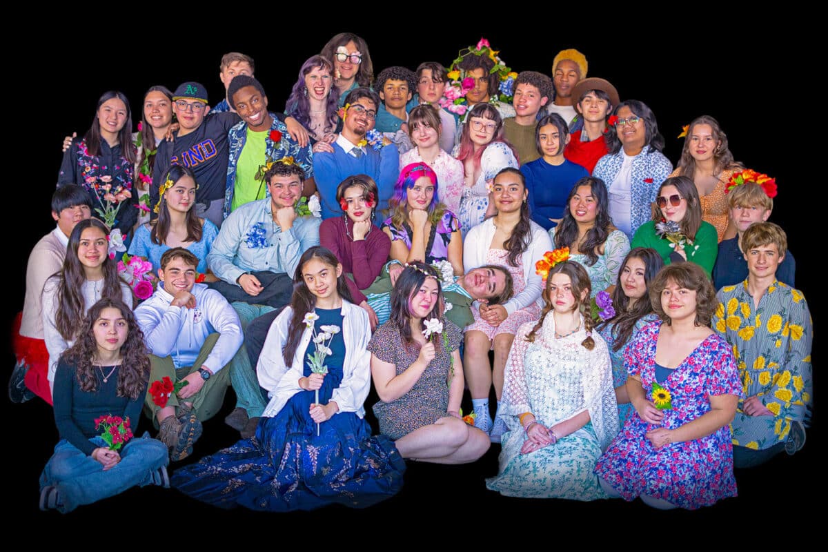Alameda Post - The full cast and crew of Hadestown Teen Edition poses together holding and wearing flowers. 