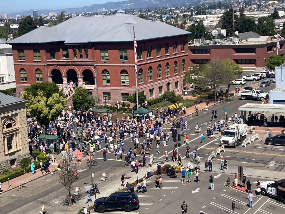 Alameda Post - A photo taken from high up of a large crowd gathered at City Hall and blocked streets around it.