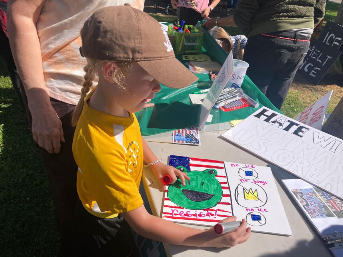 Alameda Post - A child colors a protest sign for the No Kings protest.