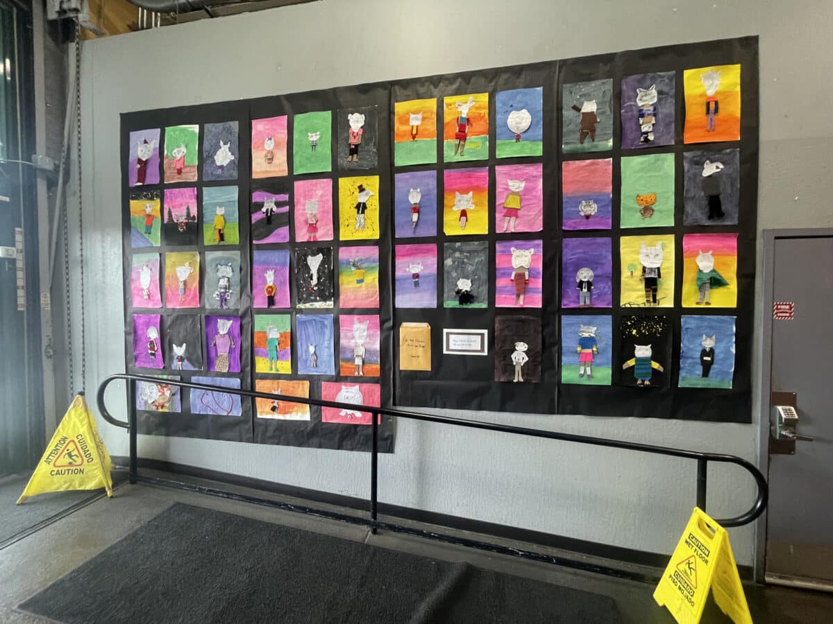 Alameda Post - A wall of colorful mixed media art projects by elementary school kids. They are all humanoid figures with large animal heads, dressed in clothes. 