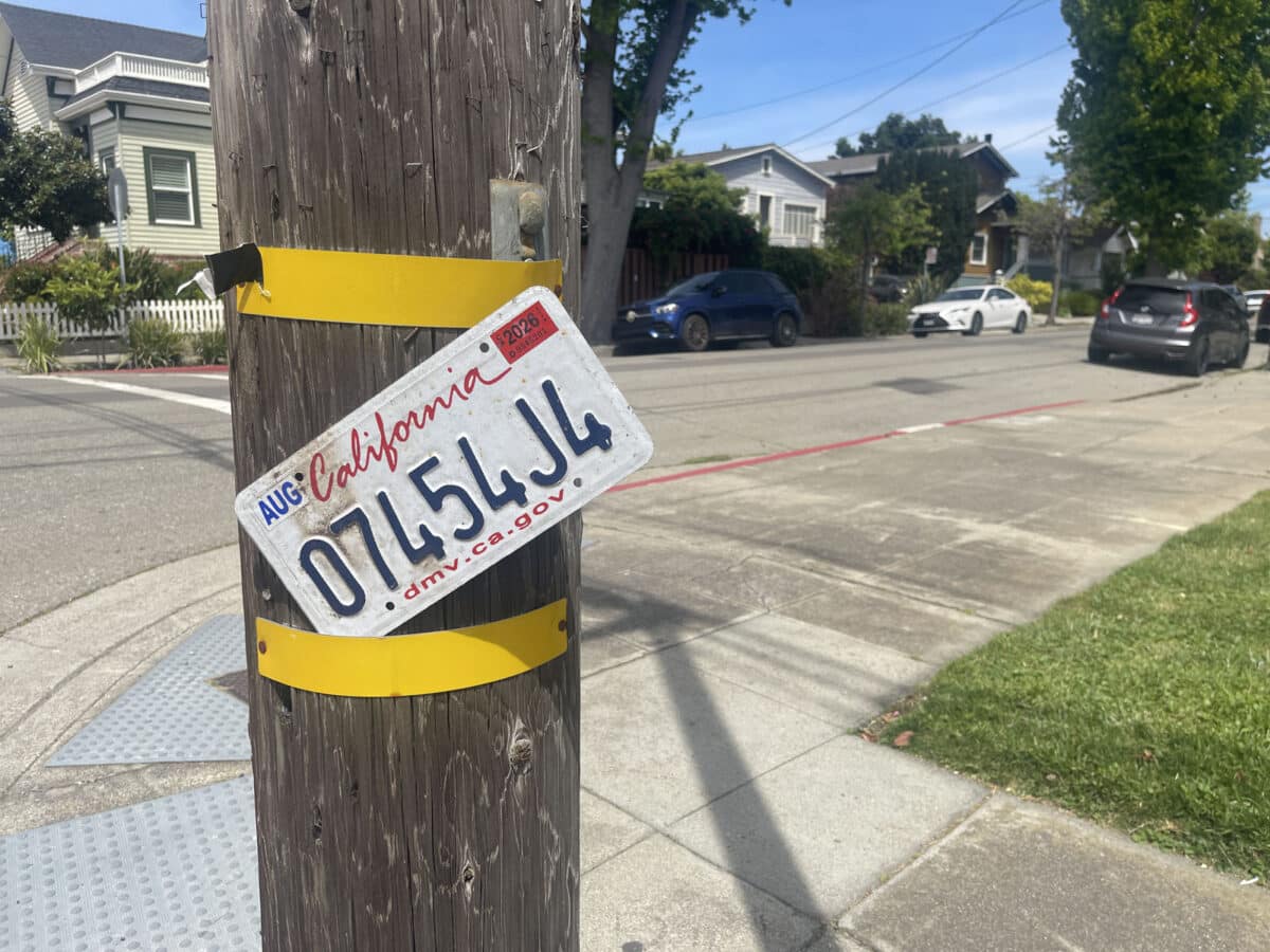 Alameda Post - A license plate loosely attached to a telephone pole.