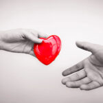 Alameda Post - A hand hands another outstretched hand a cartoon red heart.
