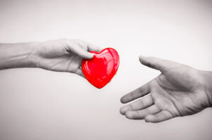 Alameda Post - A hand hands another outstretched hand a cartoon red heart.
