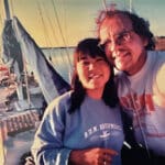 Alameda Post - A man and a woman smile at the camera, taking a selfie on a boat.