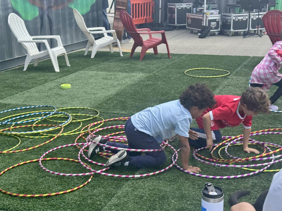 Alameda Post - Children crawl through hula hoops on the ground. 