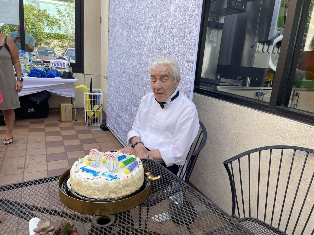 Alameda Post - Roger Goodman, wearing a tux shirt and bow tie, sits with a birthday cake.