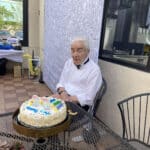 Alameda Post - Roger Goodman, wearing a tux shirt and bow tie, sits with a birthday cake.