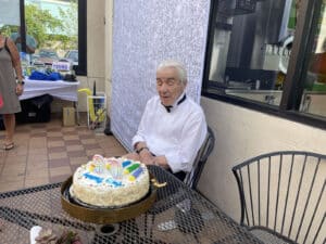 Alameda Post - Roger Goodman, wearing a tux shirt and bow tie, sits with a birthday cake.