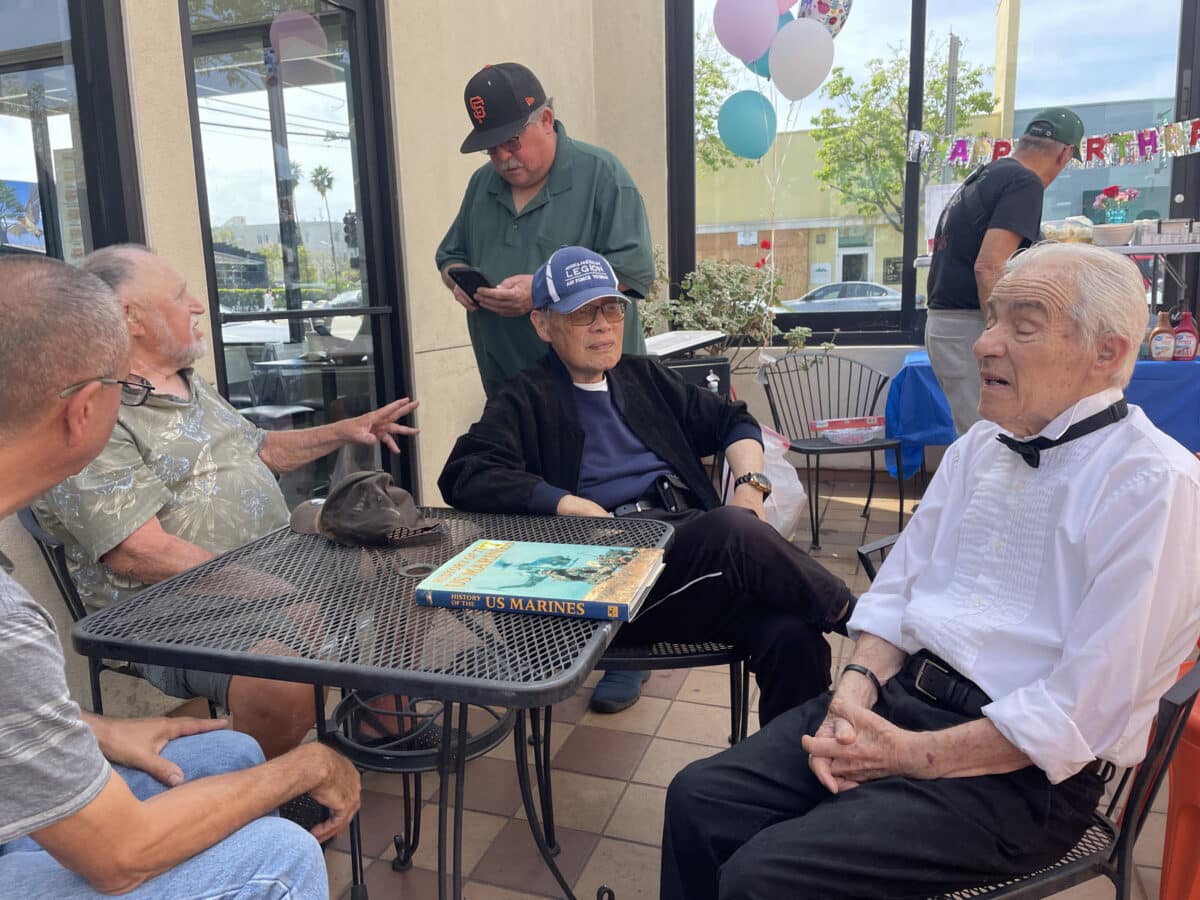 Alameda Post - Goodman sits around a table outside and chats with friends.