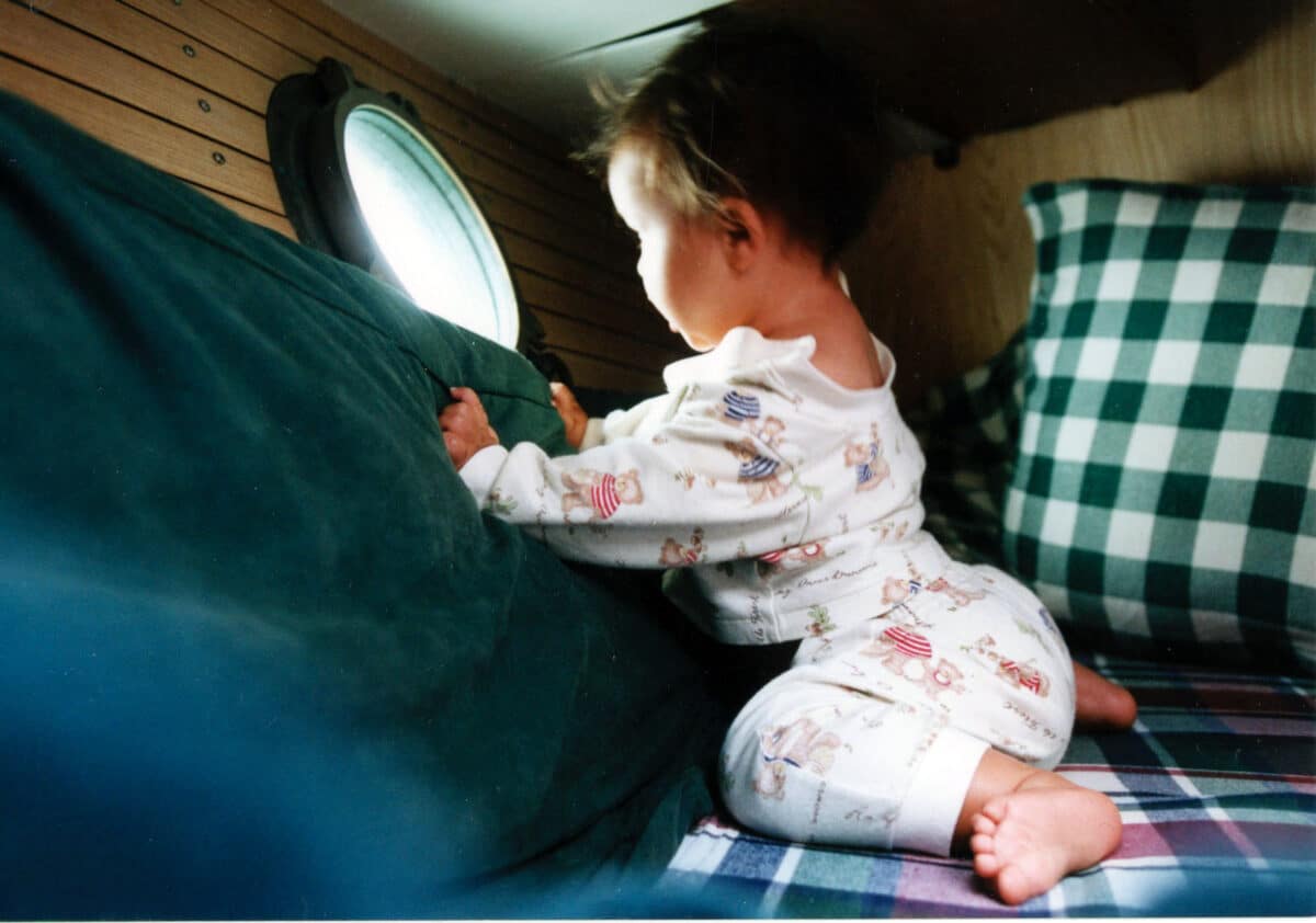 Alameda Post - A baby looks out of the porthole of a boat.