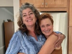 Alameda Post - Laura Louise Rhodes stands hugging a woman.