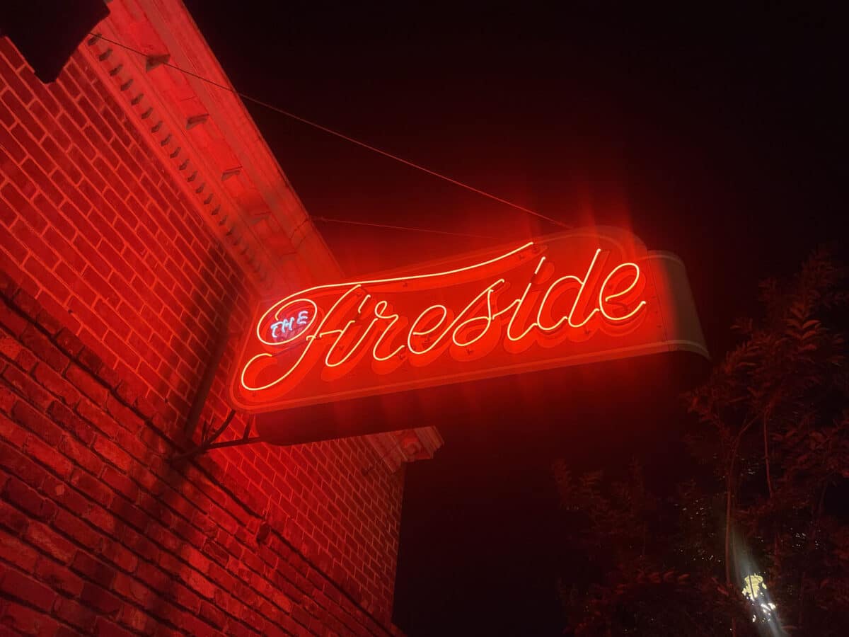 Alameda Post - The neon sign outside Fireside, lit up bright red at night.