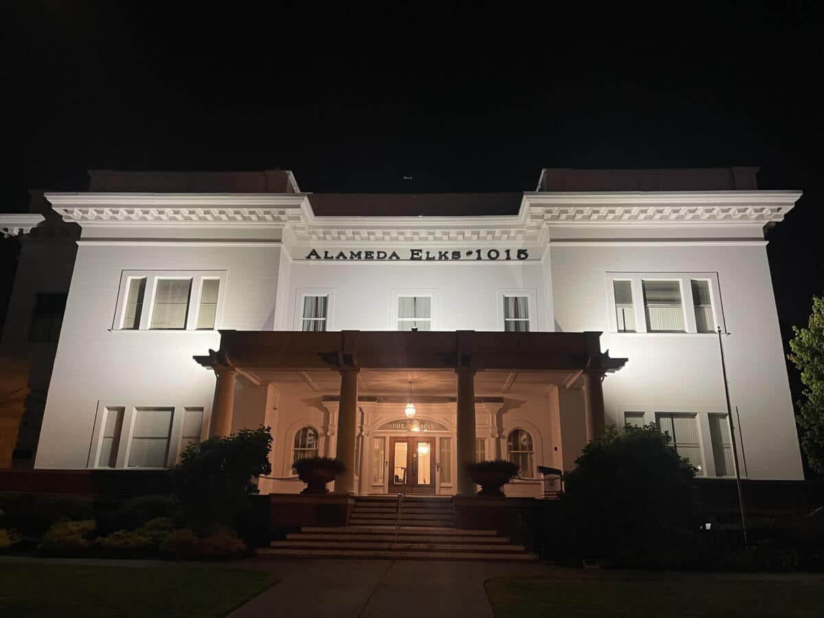 Alameda Post - A large, stately white building, lit up at night.