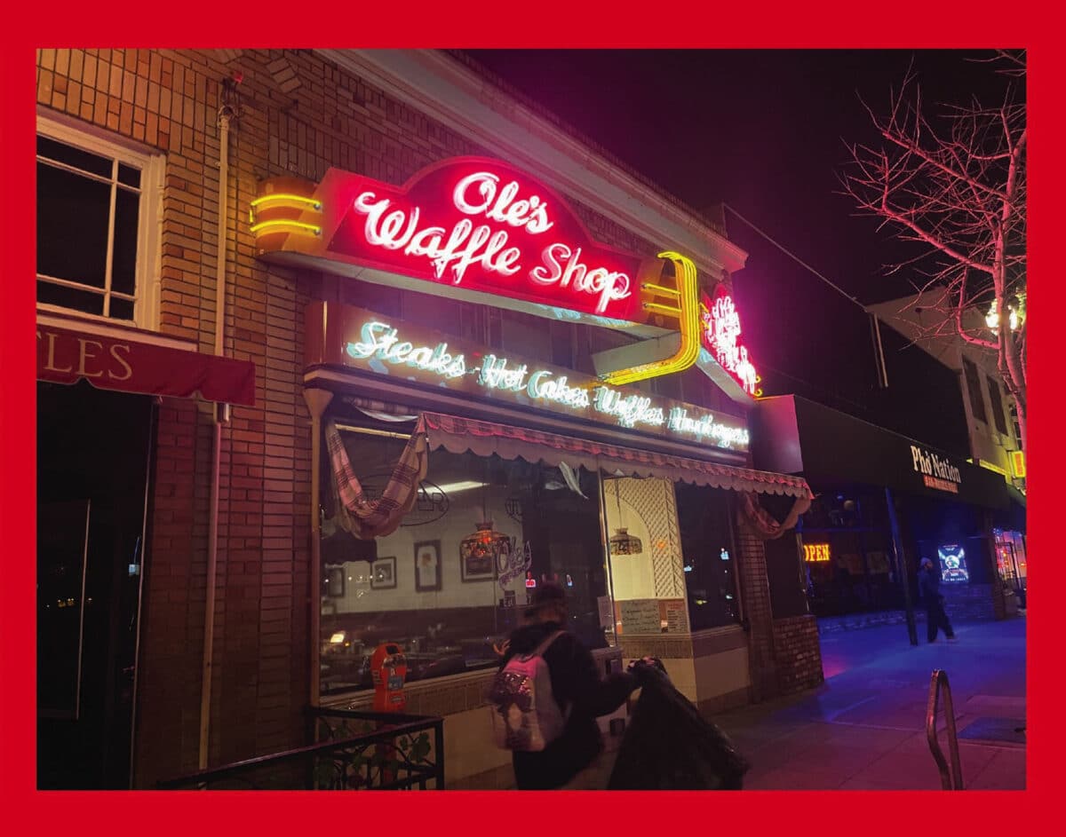 Alameda Post - The bright neon sign in front of Ole's Waffle Shop, lit up at night. 
