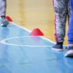 Alameda Post - People walk on a gym floor around small cones.