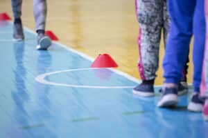 Alameda Post - People walk on a gym floor around small cones.